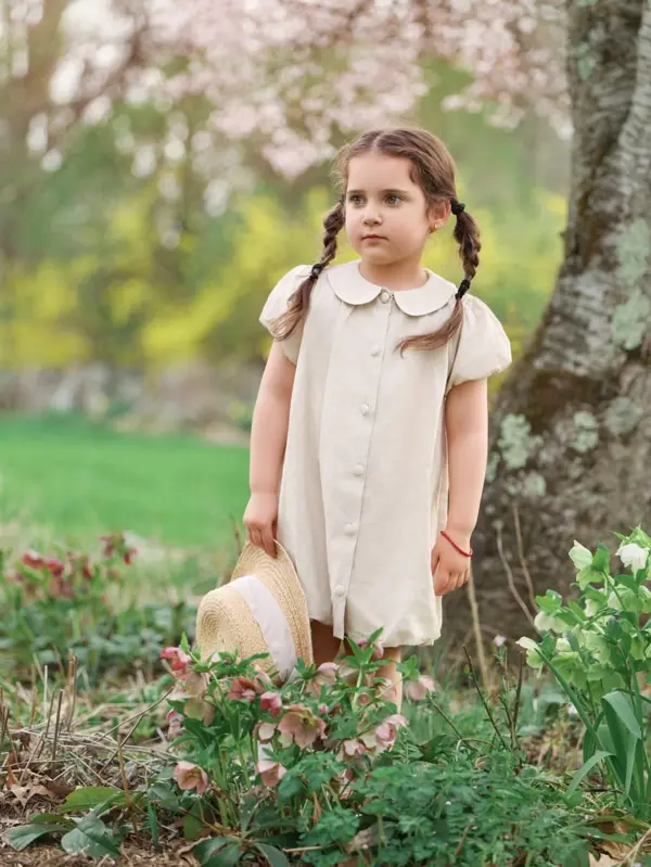 Girl with braids in a cream dress in a spring garden, outdoor photography by Photoholic, Rockland County NY
