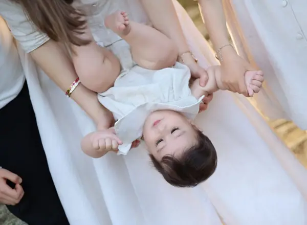 Laughing baby held upside down in a white dress, outdoor photography by Photoholic, Rockland County NY